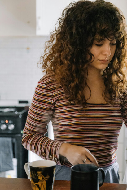 A woman makes coffee in her home kitchen, bathed in soft light and a calm atmosphere