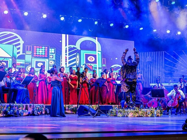 Sob luzes intensas e arranjos orquestrais, Nelson Tivane conduz o espetáculo “O Compositor” diante do coro e da Orquestra Xiquitsi. A proposta procurou unir música popular, performance coletiva e linguagem sinfónica num mesmo palco. O Centro Cultural Moçambique-China transformou-se num encontro entre coro, cordas e repertórios populares durante o concerto. A cenografia vibrante e a dimensão coletiva da apresentação marcaram a atmosfera da noite. Entre fumaça cénica, cores fortes e instrumentos acústicos, a manifestação artística apostou na grandiosidade visual e sonora para reinterpretar músicas populares moçambicanas em formato ao vivo