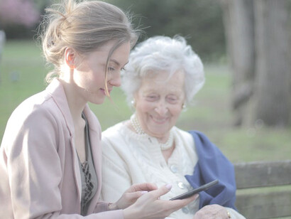 An upbeat senior mother and her adult daughter sharing a smartphone moment