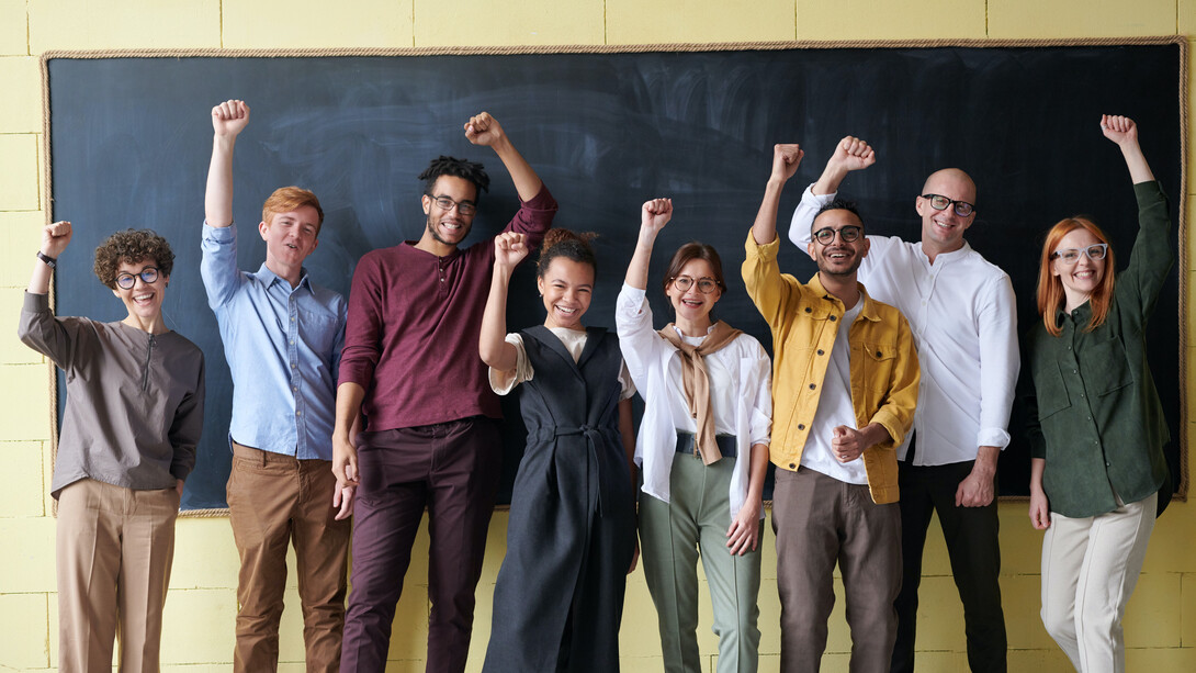 Jovens adultos de diversas culturas comemorando juntos uma apresentação em sala
