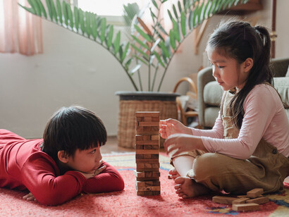 Irmãos jogam jogo com peças físicas. Os jogos promovem a sensação de recompensas