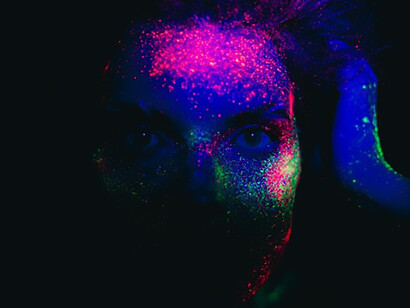 A woman's face, a canvas for a kaleidoscope of colored powders, radiating a captivating and artistic transformation