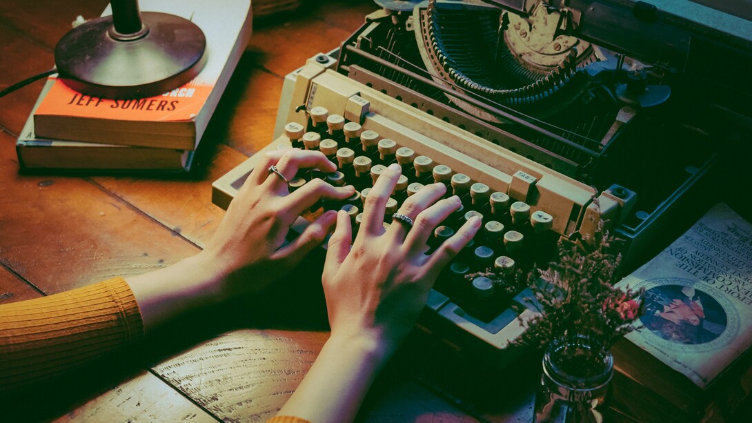 A lady busy writing on her typewriter