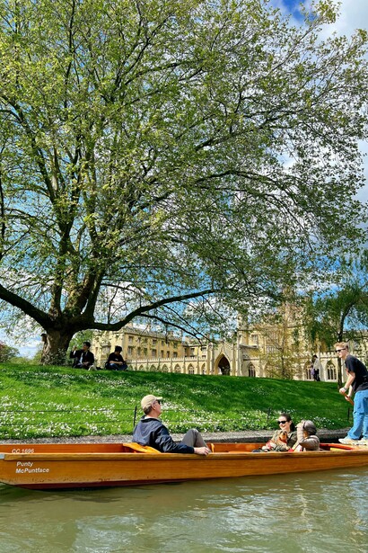 Visitors gliding along the River Cam by boat, taking in the historic sights of Cambridge, UK