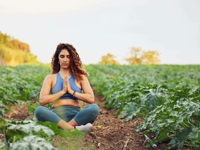 A woman in a field practicing mindfulness through yoga and meditation