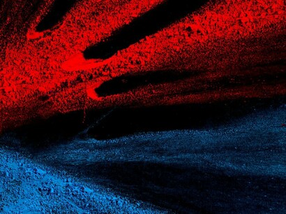 Bright red and blue Holi powder scattered on a black surface, creating an abstract art composition