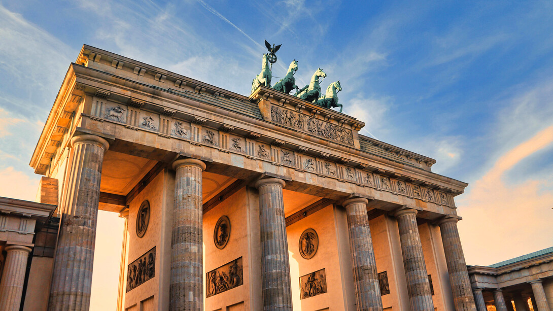 The Brandenburg Gate in Berlin, Germany, stands as a symbol of resilience, its ancient stone columns bathed in the warm glow of a Berlin sunset, reminding us of the city's journey from division to unity