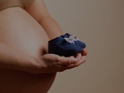 Mãe grávida segura sapatinhos de bebê