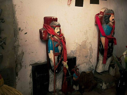 El gauchito estaba rodeado de ofrendas que sus devotos le habían dejado. Vino y cigarrillos eran los obsequios predilectos.  Escultura Gauchito Gil, Cementerio San José del Rincón, Argentina
