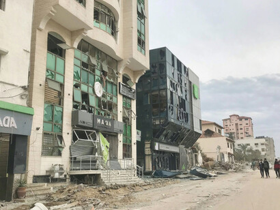 A few people walk down a dirt road amid the devastation in Gaza, following the bombing by the State of Israel that began on October 7, 2023