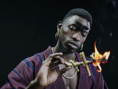 A man in maroon robe holding a burning figurine