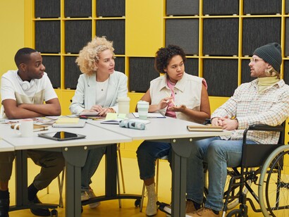 Colleagues engaged in an attentive discussion around a meeting table, representing leadership built on listening and mutual respect