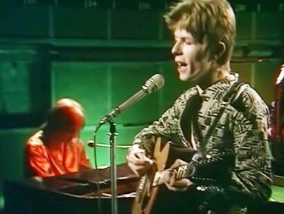 David Bowie performing a song in the 1970s on his trusted guitar