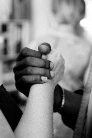 A grayscale photo of a man and woman holding hands, symbolizing connection and unity