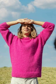 Donna all'aperto che si protegge gli occhi dal sole sorridendo: "Il giusto mix tra eyeliner e olio motore è la metafora di una donna che sa muoversi tra autonomia e connessione, indipendenza e interdipendenza, femminilità e prontezza"