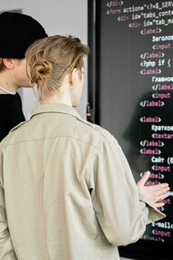 Two men reviewing code on a board, illustrating collaborative coding and the use of AI tools in development