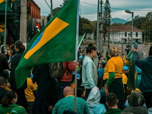 People waving Brazilian flags at a political gathering, representing the struggle for power between rival political camps