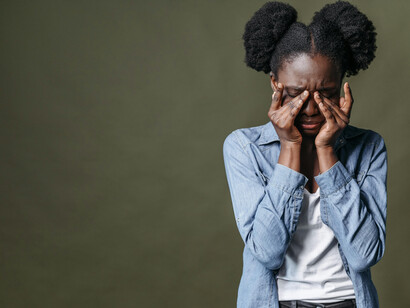 A woman wearing a blue denim jacket holds a brown cardboard sign, symbolizing silent struggle and the experience of feeling overlooked
