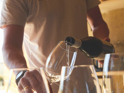 A man is carefully pouring wine into elegant bottles, ensuring a precise and artful process