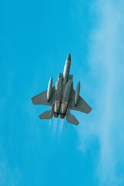 Un avión de combate militar ascendiendo en un cielo azul despejado, representando el poder militar que moldeó el mundo de la Guerra Fría