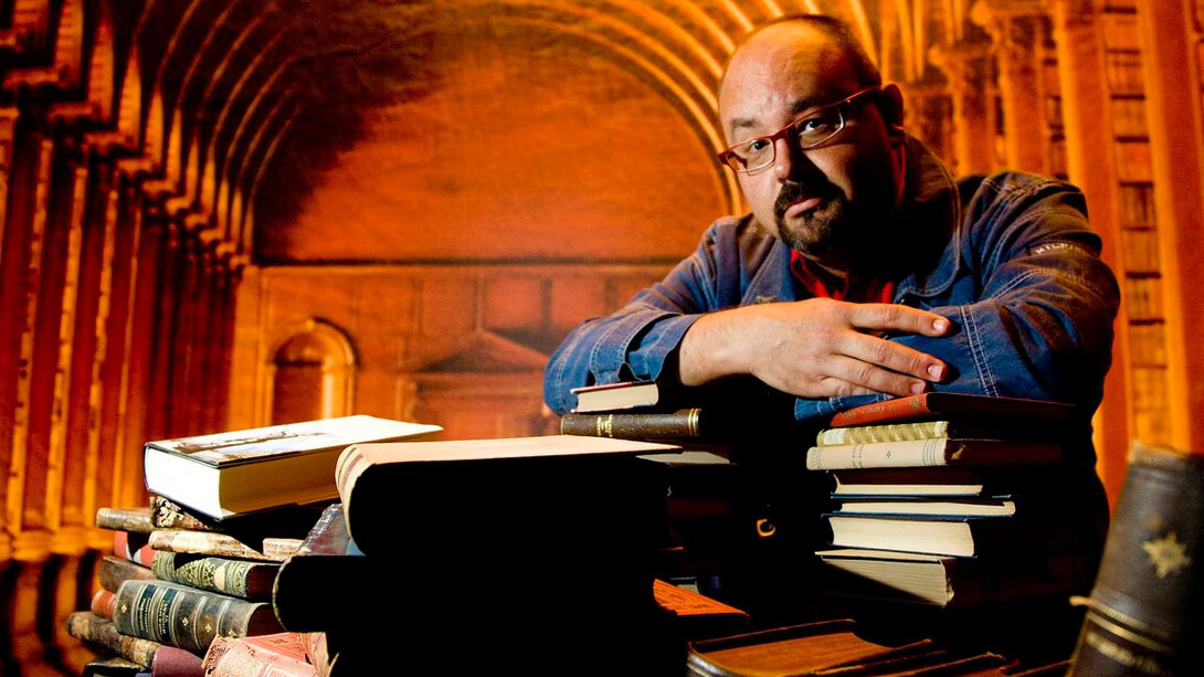 Carlos Ruiz Zafón apoiado sob livros 