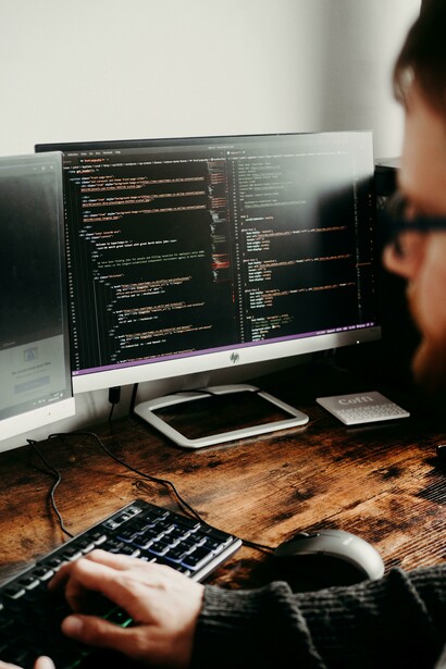 A man sitting at a desk working on his computer, focused on coding