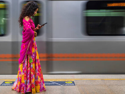 An Indian girl checking her mobile phone while waiting at a metro station in India
