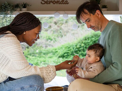 A family embracing nature while living and traveling in a campervan, sharing the adventure with their baby