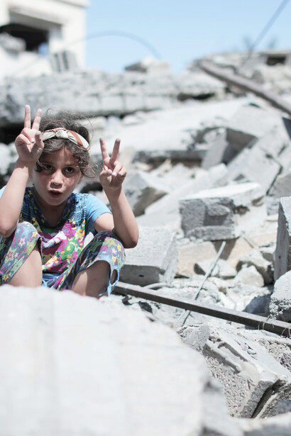A child sitting on rubble in Gaza, Palestine