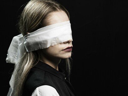 Mulher angustiada, com olhos vendados. Em certas circunstâncias, preferimos trocar a dor aguda de enfrentar uma situação, pela dor crônica de conviver eternamente com o problema. E aí só nos resta esconder o sofrimento, tentar ignorá-lo, aprender a conviver com ele, passar aos outros a aparência de que ele não existe e remoer solitariamente o martírio. 
Isto pode até não nos levar à morte, mas tem chance de tirar a alegria de nossa vida, o que é quase o mesmo. Buscamos refúgio e encontramos prisão