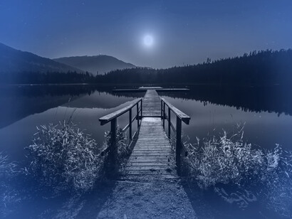 A dock over the lake at night during a full moon