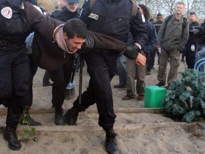 French gendarmes evacuate immigrants from an improvised camp