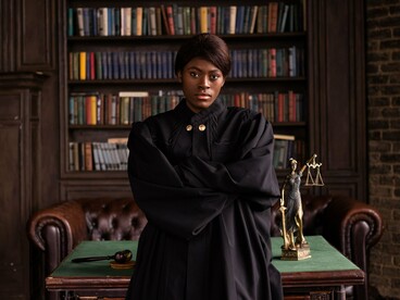 A composed judge in formal robes before symbols of justice, reflecting the foundation of legal integrity