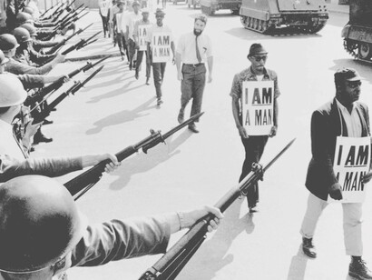 Civil rights activists are blocked by National Guardsmen brandishing bayonets while trying to stage a protest on Beale Street in Memphis, Tennessee. The marching demonstrators are also flanked by tanks