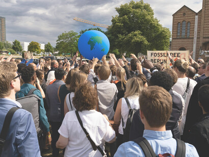 People gather at a climate demonstration carrying a large Earth globe, expressing collective concern for the future of the planet in Berlin, BE, Germany