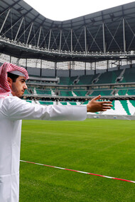 Pessoa de nacionalidade árabe mostra estádio de futebol em Doha, Catar. Foto de Kai Pfaffenbach