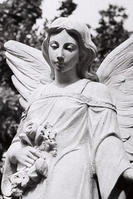 A black and white photograph of an angel statue in a cemetery