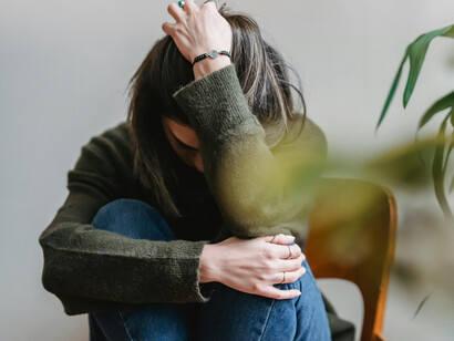 A young woman hugging her legs, anguished