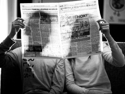 Dos lectores absorbidos por la lectura de su periódico, simbolizando el poder de la censura y la manipulación de los medios