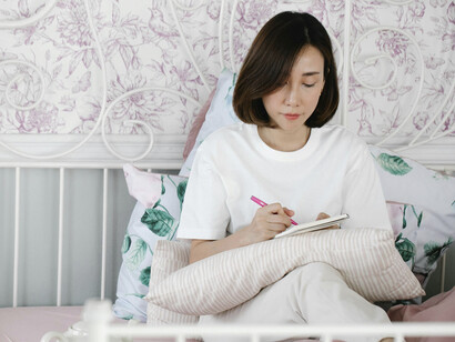 Una mujer escribe en su cuaderno en su habitación