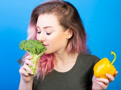 A woman with a healthy lifestyle inspecting fresh broccoli, red and yellow peppers, essential Mediterranean diet ingredients that nurture the gut-brain axis and enhance gut health in nutritional psychiatry