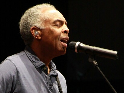 Gilberto Gil canta de olhos fechados durante apresentação no Festival de Cornouaille, em Quimper, França, em 2010. A concentração diante do microfone traduz a intimidade de quem transforma a música em experiência e memória. Passando por diferentes palcos e gerações, sua música permanece como uma espécie de Tempo Rei, atravessando o tempo e se reencontrando com as histórias pessoais de seus ouvintes