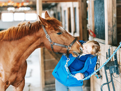 A woman taking care of her horse gives them a quick smooch