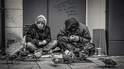 Homelessness and poverty manifesting in men begging on the streets of the UK, highlighting the urgent social issue of unemployment and its impact on lives