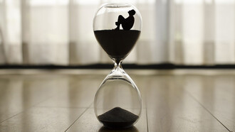 An hourglass resting on the floor, time slipping away, a poignant symbol of life's transience