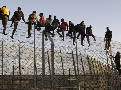 Agentes de policia e inmigrantes en la valla de Melilla
