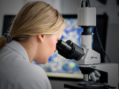 Female researcher working with a microscope in a modern biomedical laboratory environment