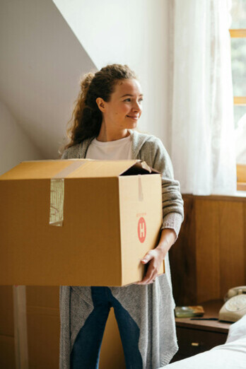 A woman organizing boxes in her room while preparing to move into a new home for a fresh beginning