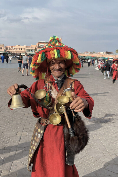 Sous les couleurs éclatantes de son chapeau et le tintement du métal à Marrakech, il avance comme une figure sortie d’un ancien conte marocain