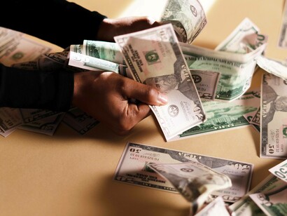 A man holding dollar bills in his hand as his way to express his commitment to the current economy network